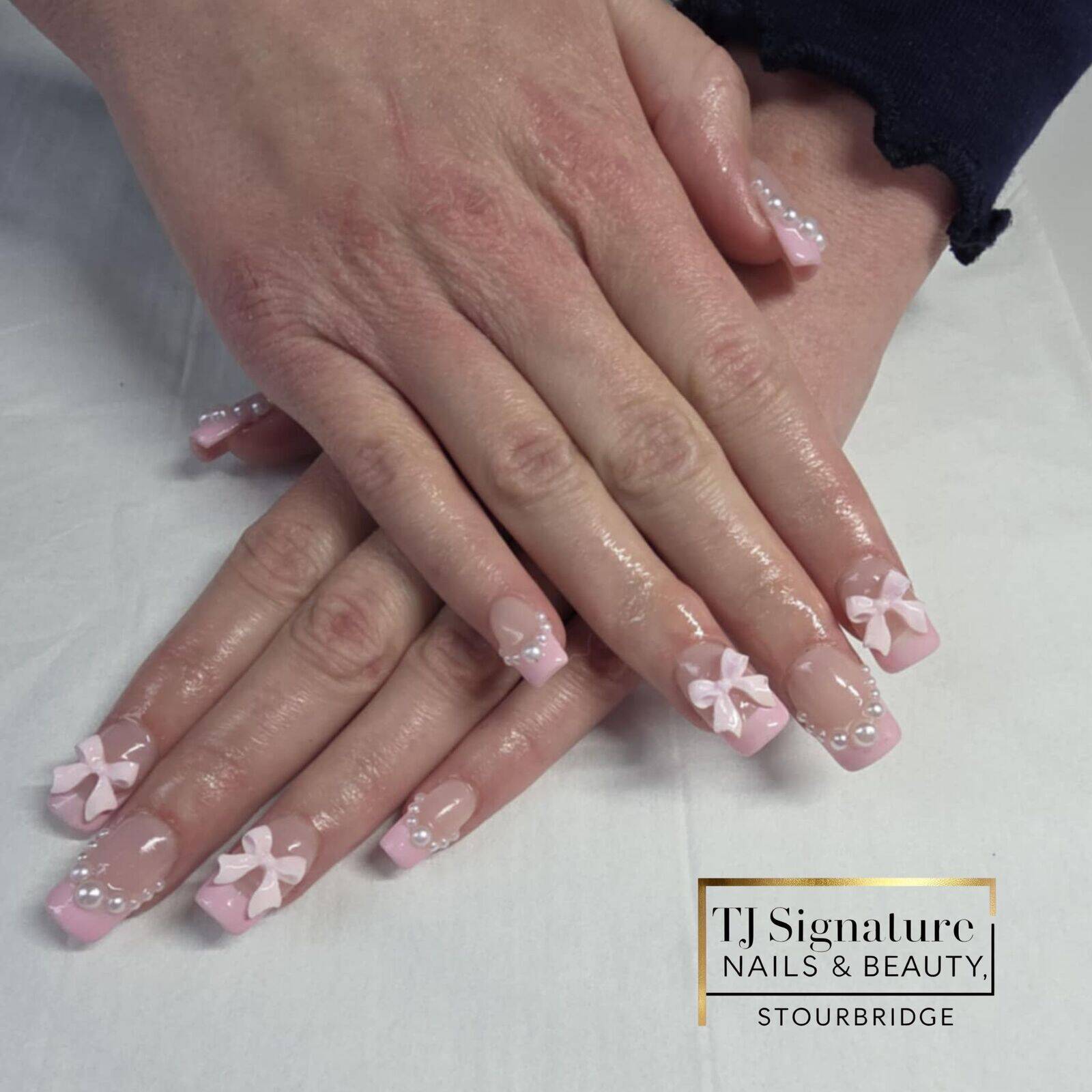 Soft pink French nails with 3D bows and pearl accents. A delicate, feminine design that blends elegance and charm – perfect for any occasion.