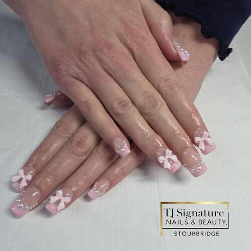 Soft pink French nails with 3D bows and pearl accents. A delicate, feminine design that blends elegance and charm – perfect for any occasion.